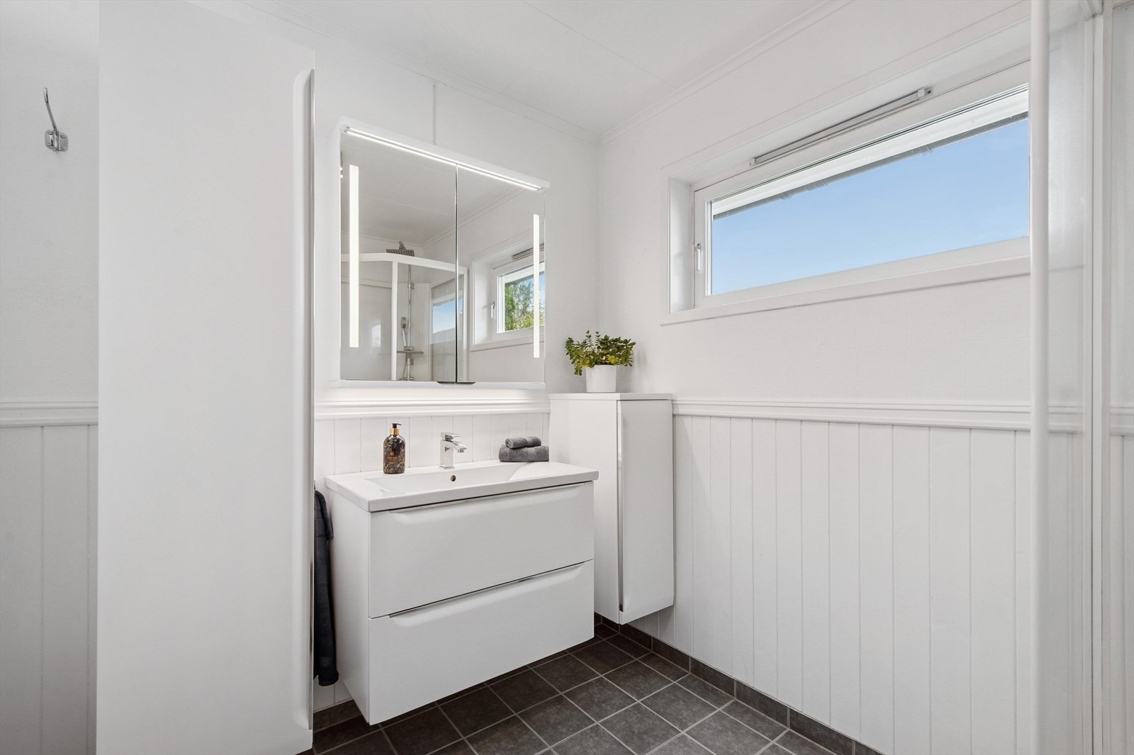 Rommet har flislagt gulv, brystningspanel på veggene og et vindu som gir dagslys. Galleribilde