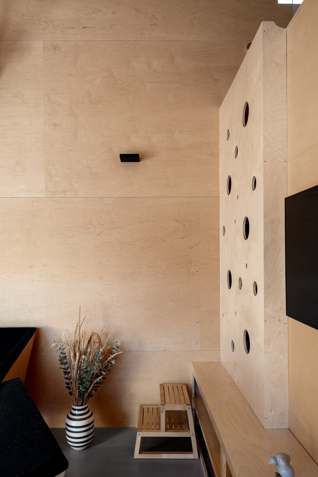 Designet med de sirkulære hullene går igjen i hytten. Her benyttes de som trapp/stige opp til hems. Galleribilde