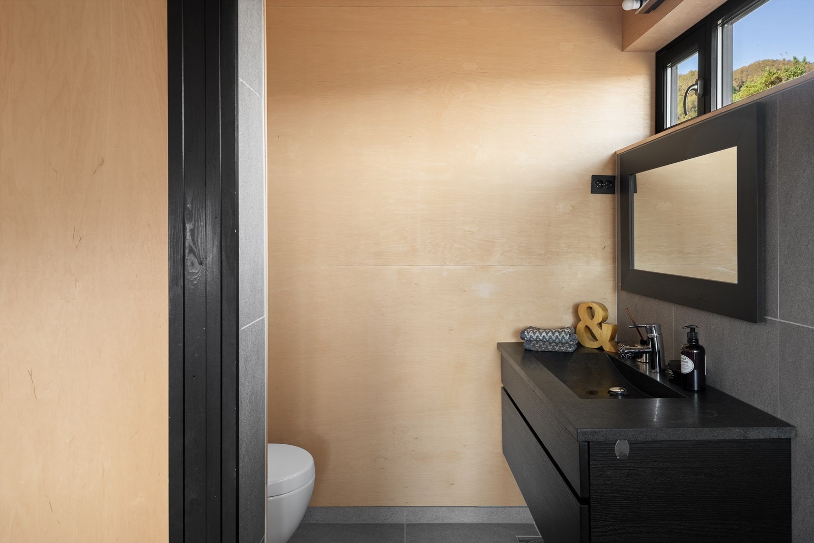 Direkte tilgang fra soverommet er det eget bad. Innredet med sort seksjon med skuffer og toalett. Galleribilde