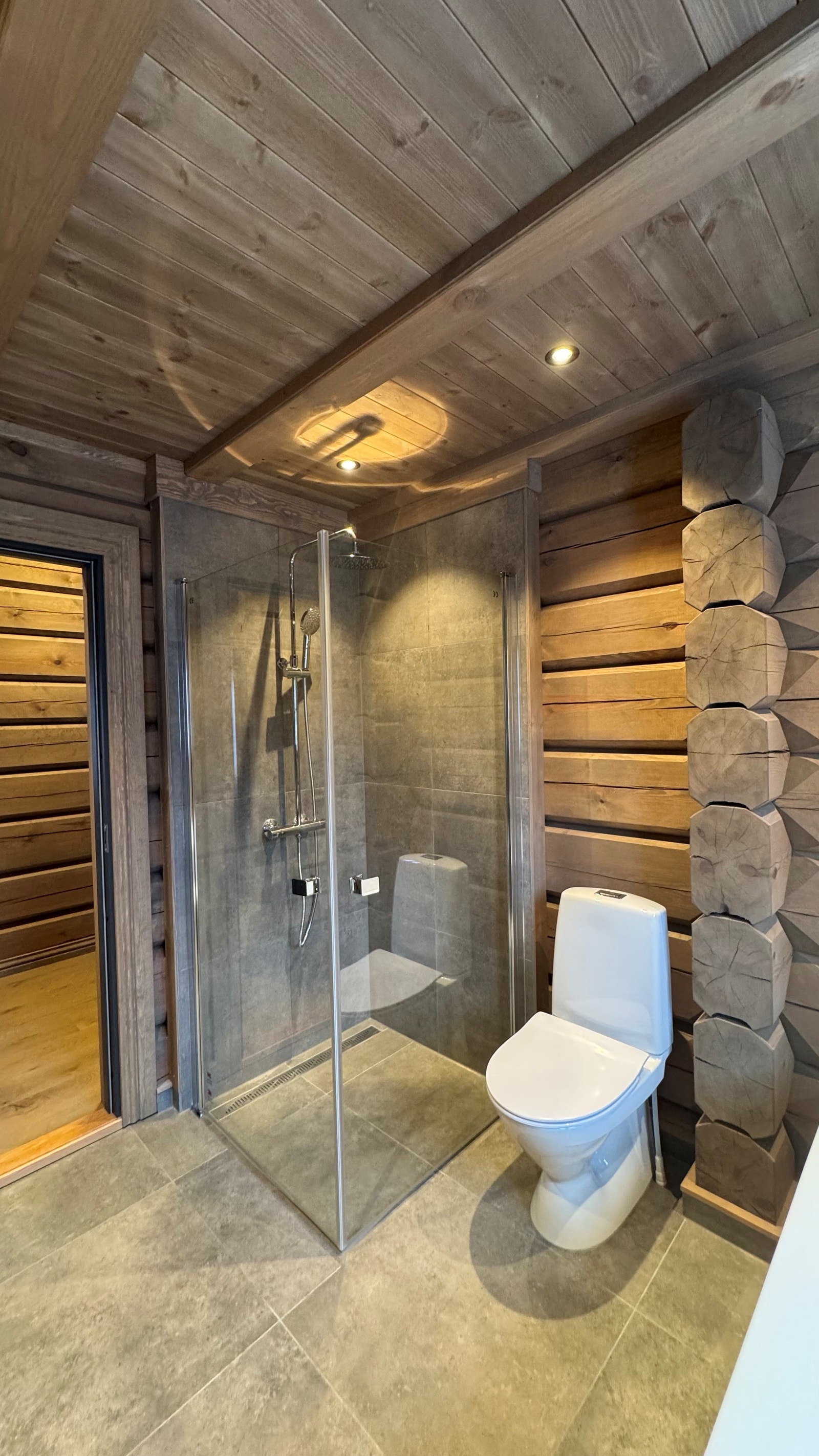 Hytta har et delikat og fullt utstyrt bad. Badet er utført med moderne, grå fliser på gulv, og flis i dusj-sone forøvrig tømmer på vegg. Baderomsinnredning fra Kistefos. Galleribilde