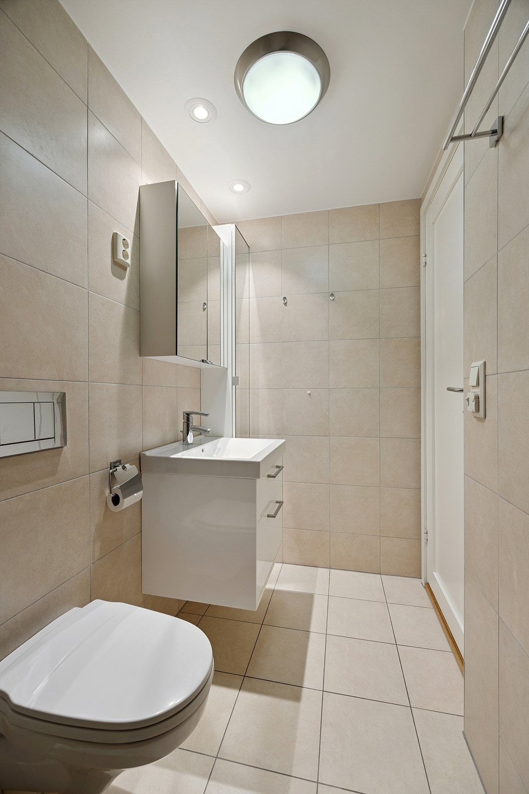 Badet er utstyrt med vegghengt toalett, servant og dusjhjørne med glassvegger. Galleribilde