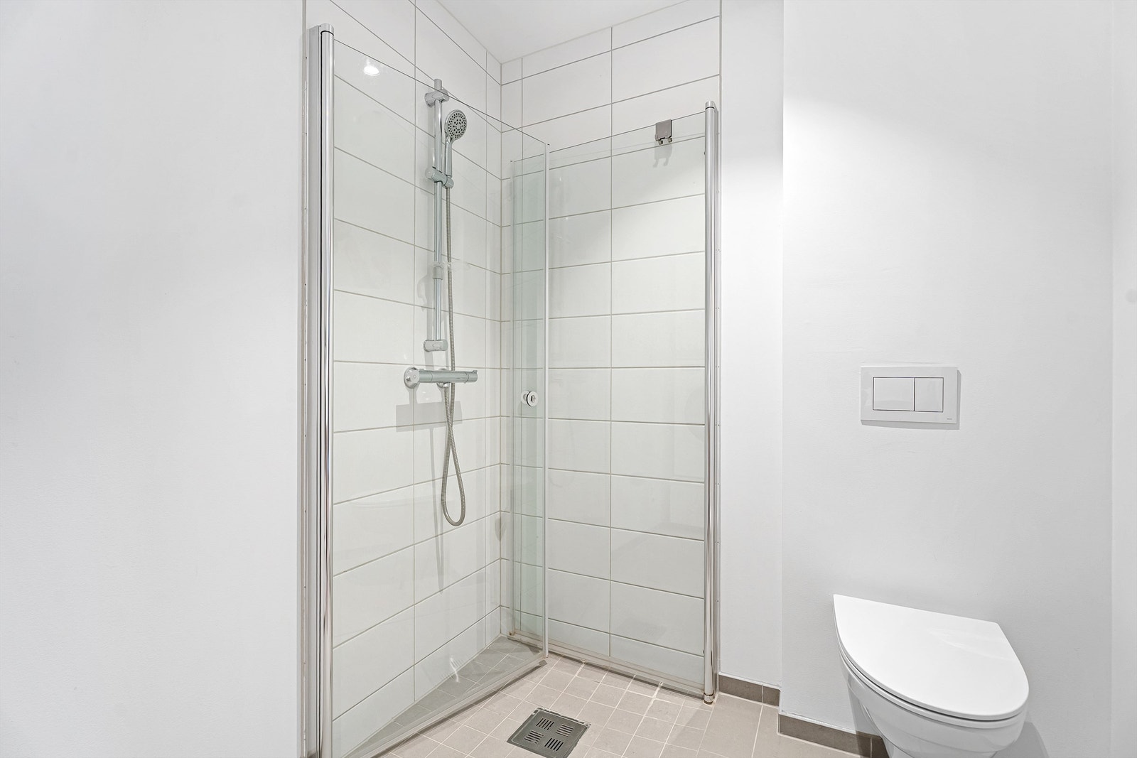 Badet har flislagt gulv og dusjsone Galleribilde