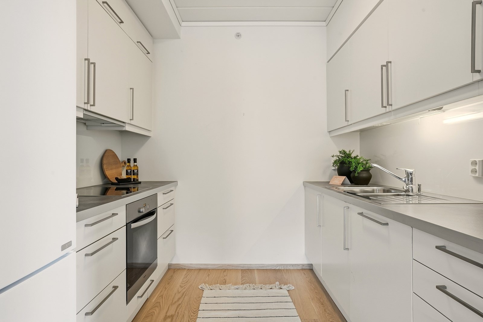 Pen kjøkkeninnredning med hvite, slette fronter og benkeplate av laminat. Galleribilde