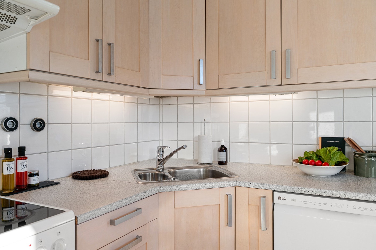 Kjøkkenet er innredet med frittstående hvitevarer som komfyr, oppvaskmaskin og kjøle/fryseskap Galleribilde