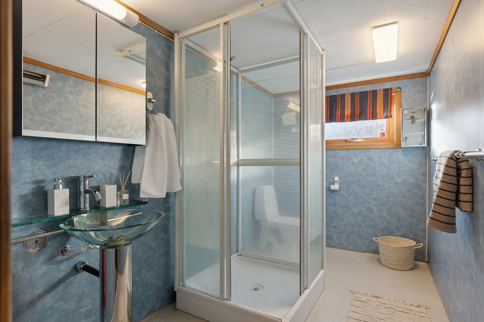 Enkelt baderom utstyrt med dusjkabinett, gulvstående toalett og servant. Galleribilde