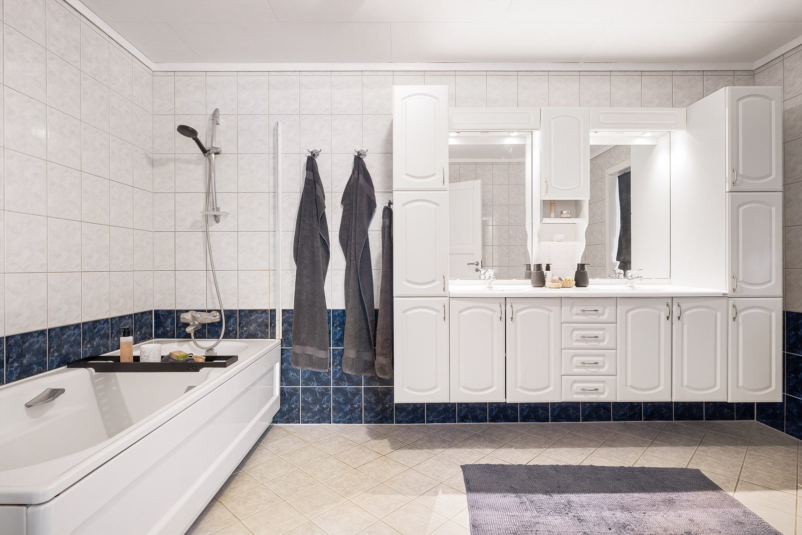 Badet er helfliset med behagelig varme i gulv | Badekar m/ dusj, toalett og baderomsinnredning med heldekkende servant samt belyst speil. Galleribilde