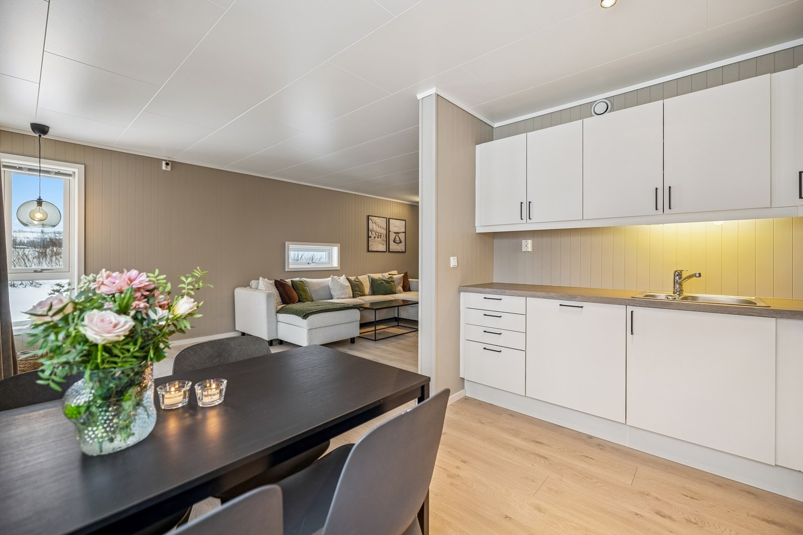 Gjennomgående laminatgulv og malte panelplater på veggene skaper en helhetlig stil. Galleribilde