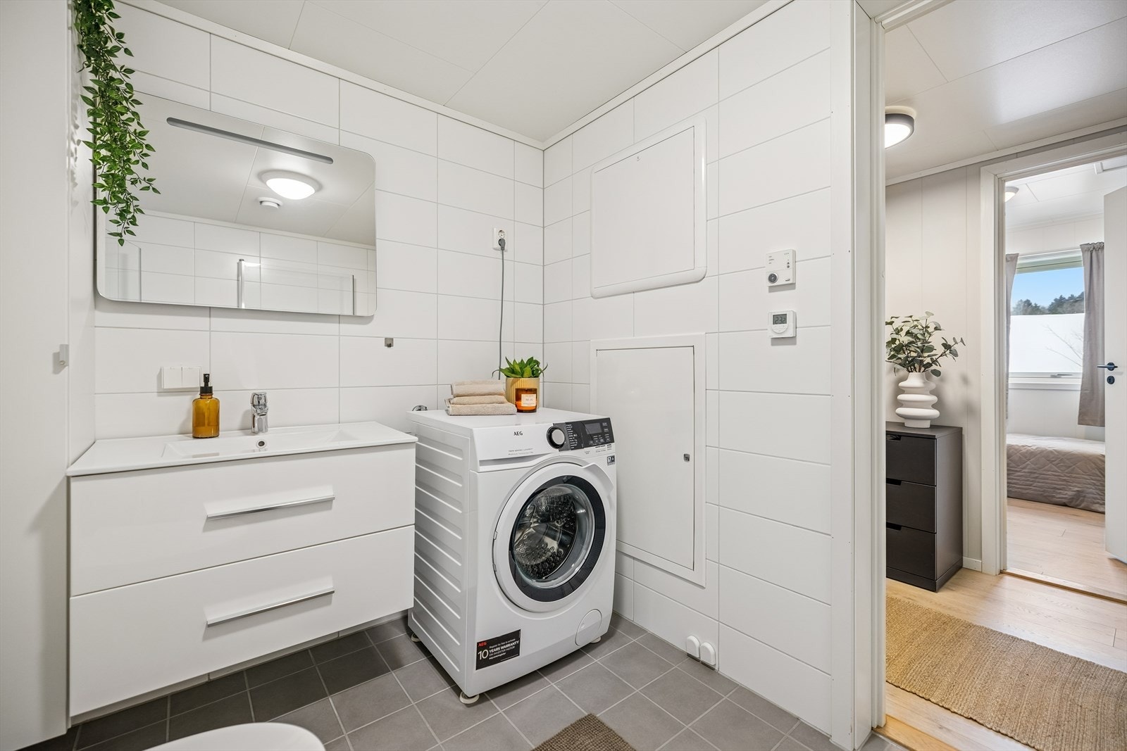 Badet er nøytralt flislagt, dette skaper en tidløs og rolig base. Opplegg for vaskemaskin og tørketrommel. Galleribilde