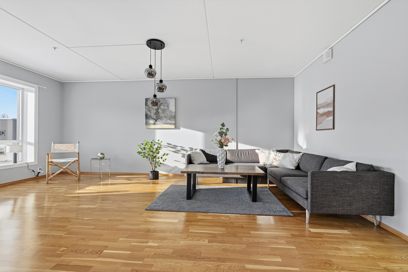 Stilren stue med parkett på gulv og slette, lyse vegger. Galleribilde