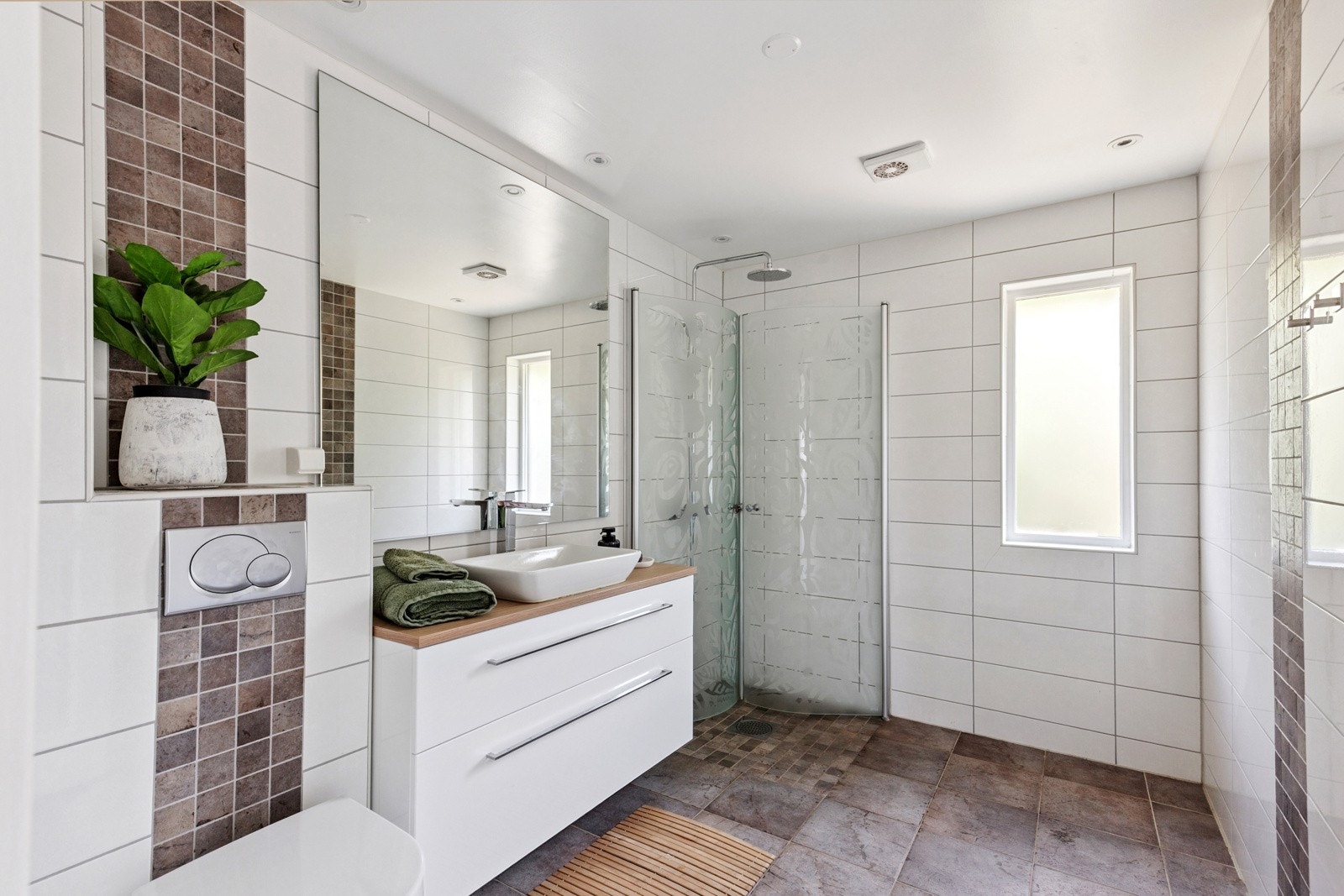 Moderne bad med fliser på både gulv og vegger, dusjhjørne og vegghengt toalett. Det er ett bad i hver etasje. Galleribilde