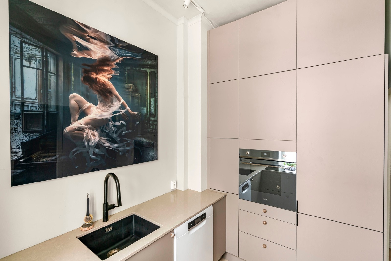 Glatt, malt veggflate over benkeplaten. Belysning via spottskinne i himling. Galleribilde