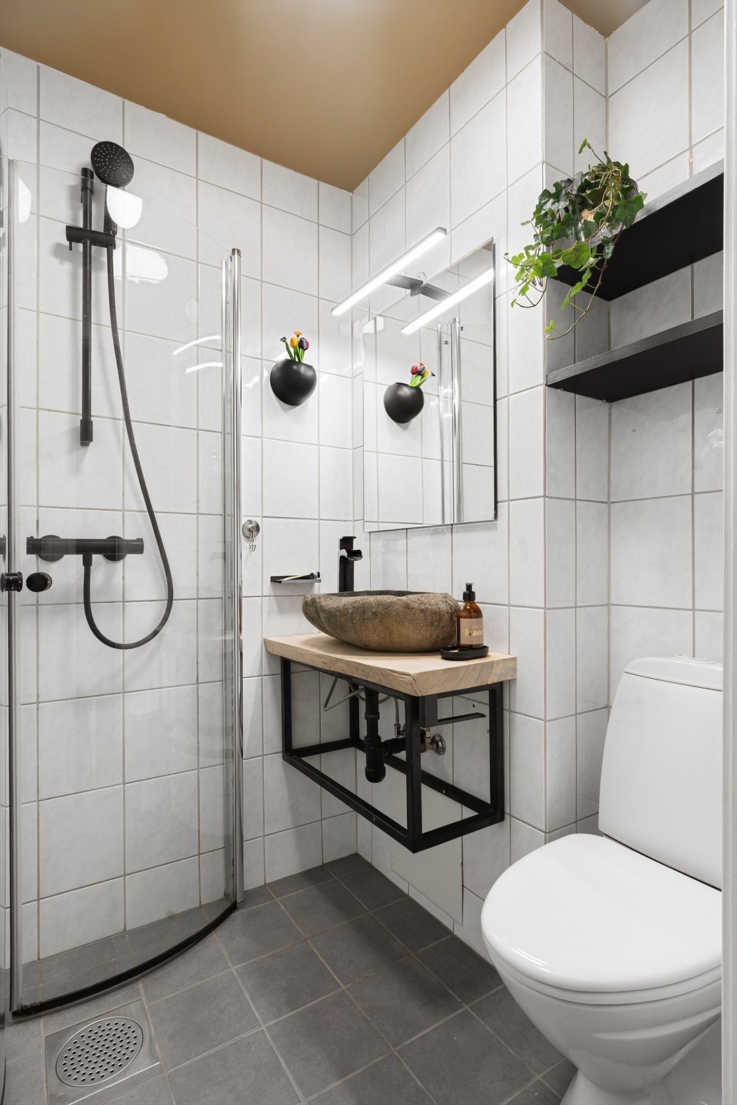 Baderommets innredning består av servant, speil med ledlys, wc og dusjhjørne med svingdører. Galleribilde