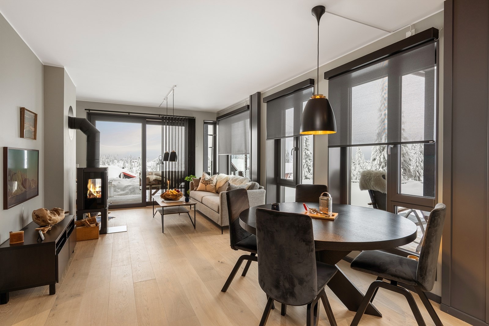 Lyst oppholdsrom med store vindusflater og monterte screens Galleribilde