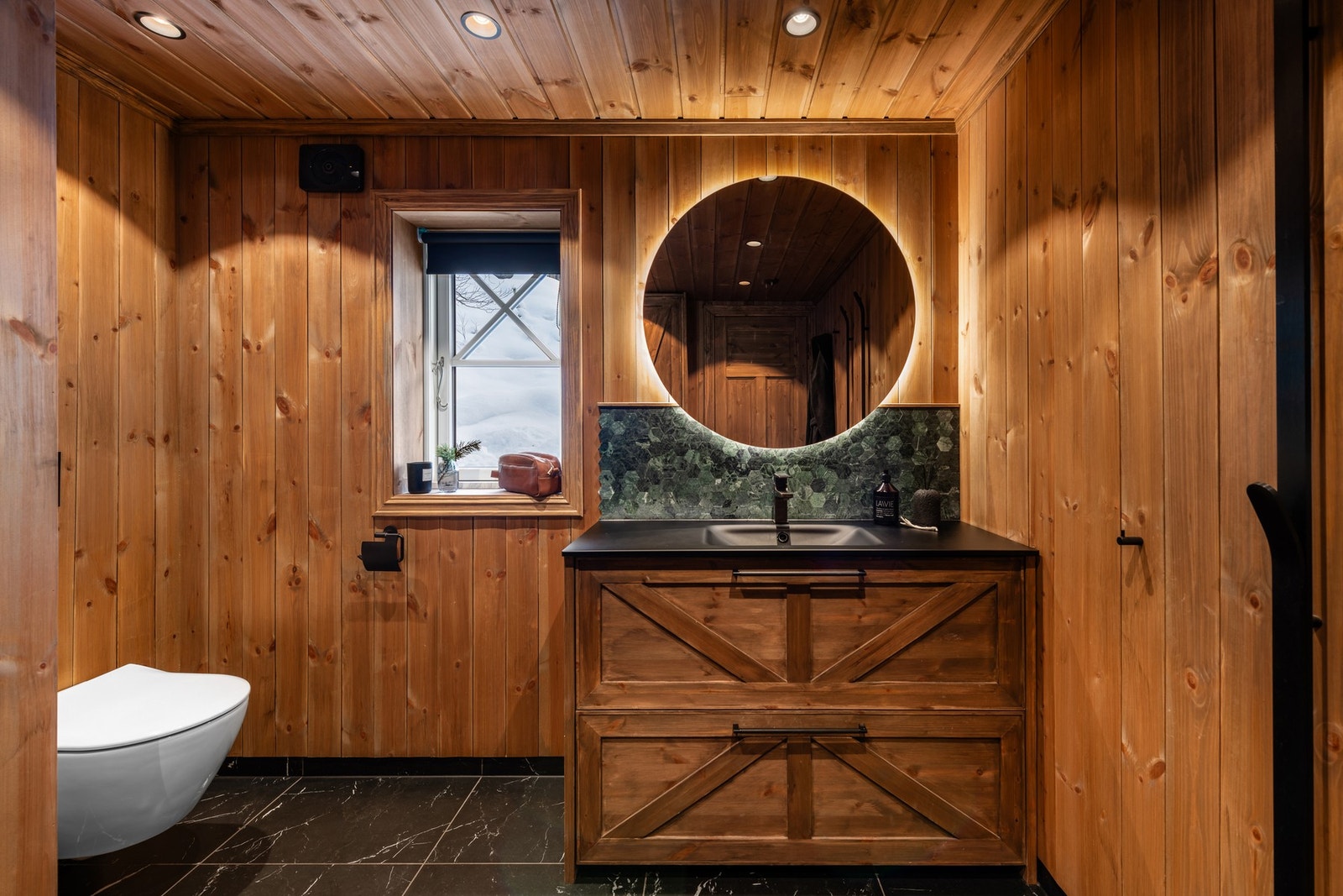 Badet er innredet med dusjplass med stor regndusj, vegghengt toalett, baderomsinnredning med håndvask og opplegg for vaskemaskin Galleribilde