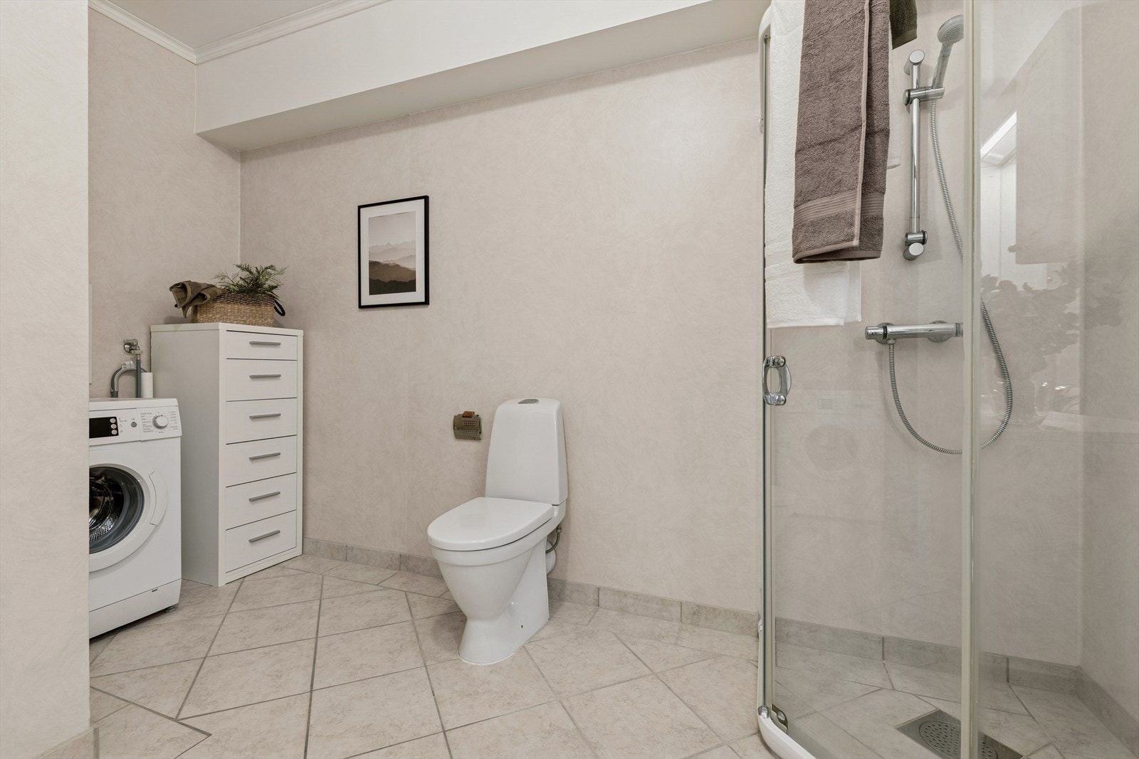 Baderommet er innredet med lyse, sjatterte fliser på gulv og lyst belegg på vegg. I gulvet har man også varmekabler for ekstra komfort. Galleribilde