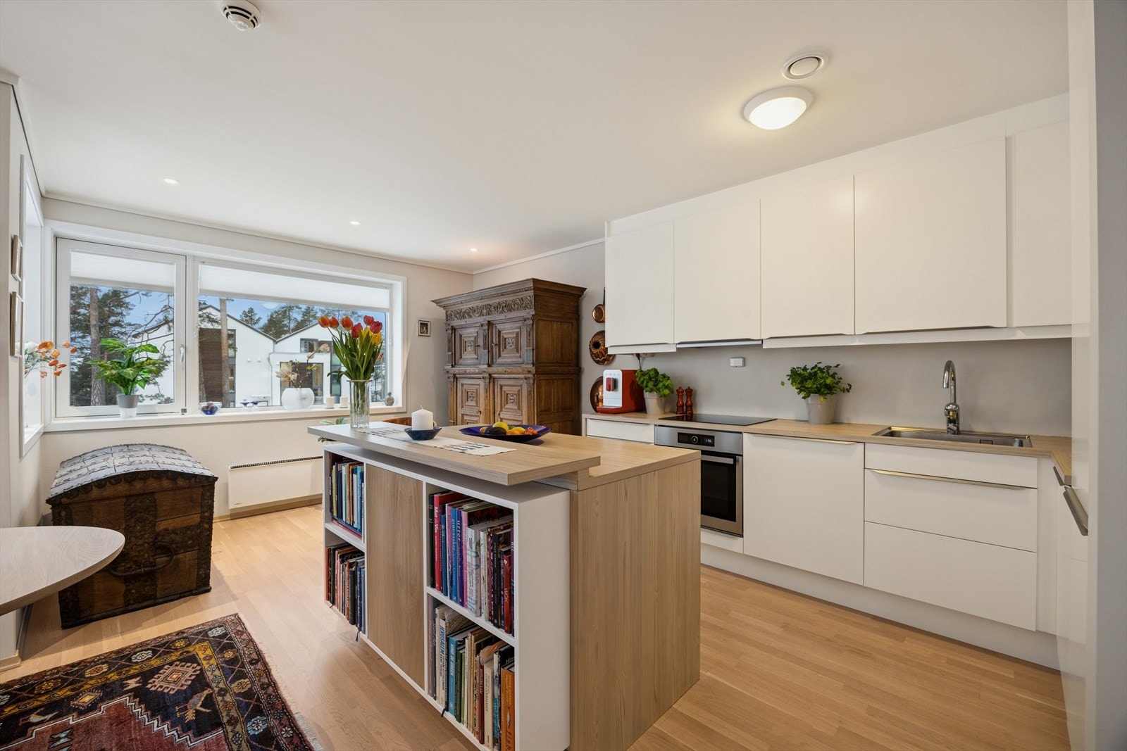 Stilrent kjøkken med kjøkkenøy og integrerte hvitevarer som stekeovn, koketopp, oppvaskmaskin og kombiskap. Galleribilde