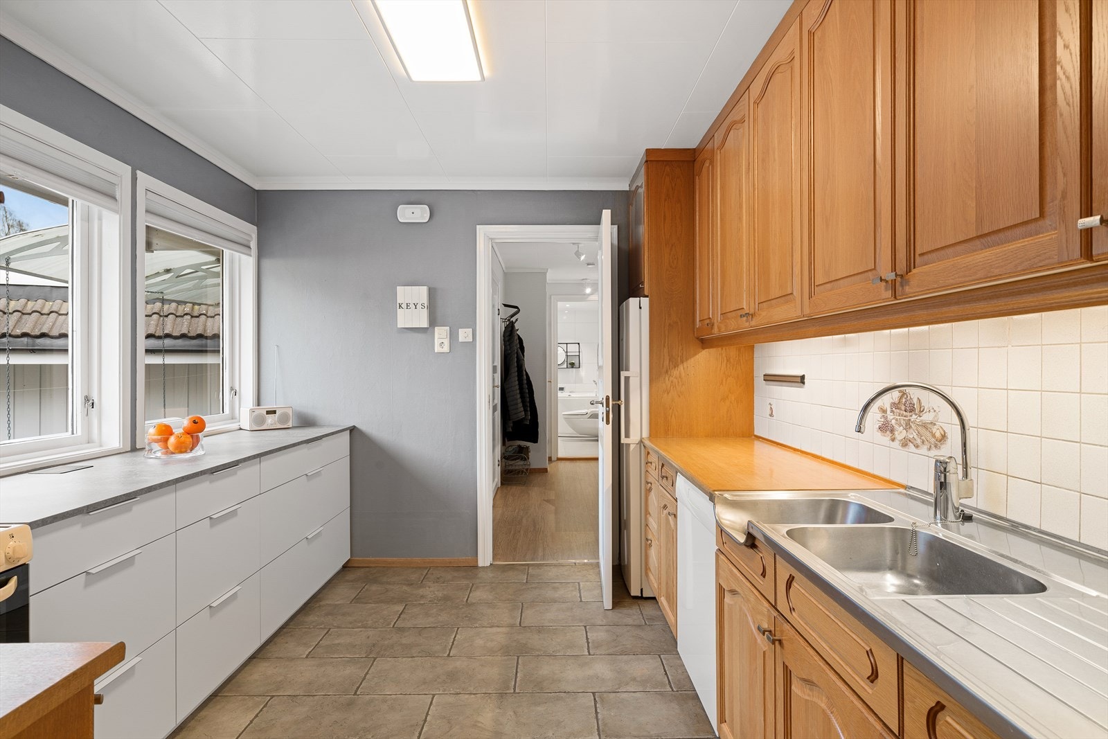 Kjøkken med fliser på gulv. Eikeinnredning med god lagringsplass i skuffer og skap. Galleribilde