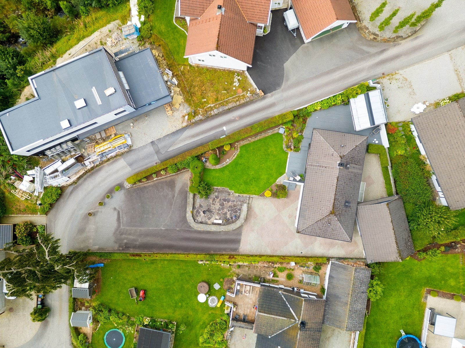 Pent opparbeidet tomt med asfalt, murer, plen, terrasser og beplantning. Svært romslig, flat og solrik tomt Galleribilde