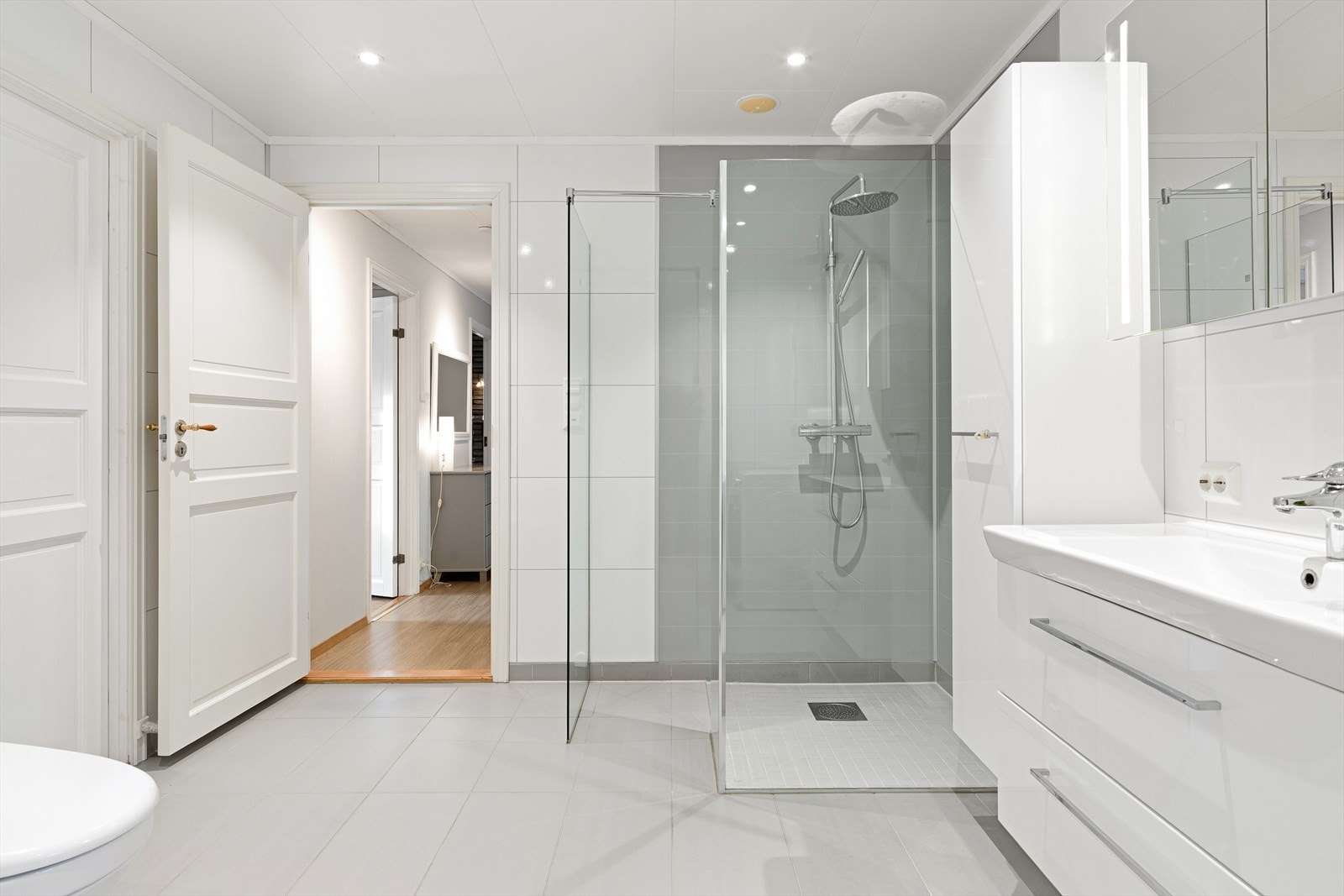 Stor dusj med glassvegger og vask i seksjon. Speilskap med belysning. Opplegg for vaskemaskin. Galleribilde