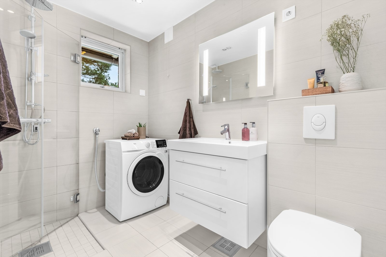 Badet er utstyrt med servant, veggmontert toalett, dusjhjørne med innfellbare dusjvegger og opplegg for vaskemaskin. I tillegg har baderommet et koselig vindu med ekstra lysinnslipp. Galleribilde