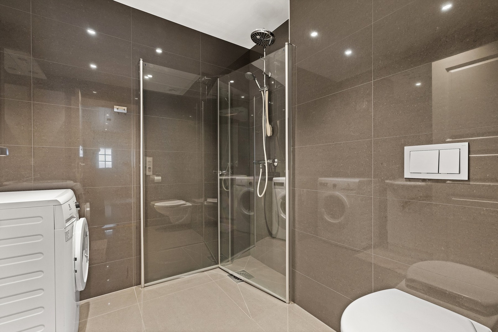 Dusjløsning med glassvegger og opplegg for vaskemaskin. Galleribilde