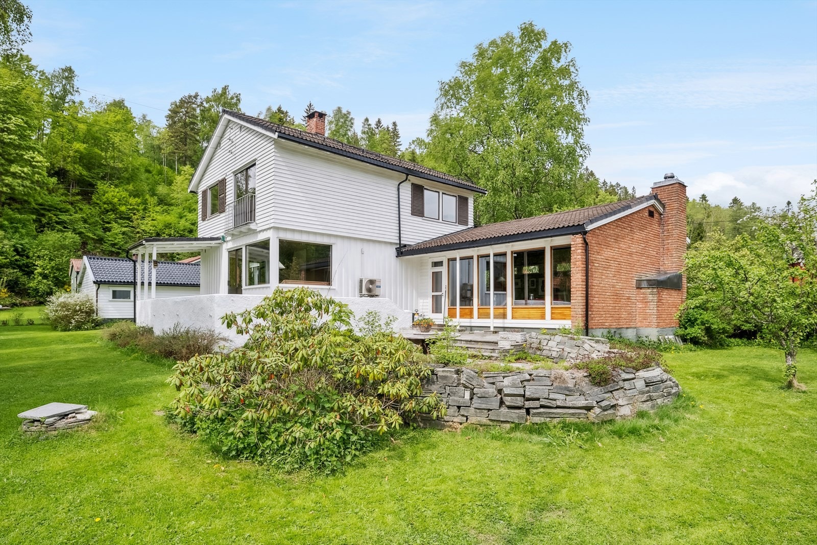 Fra stuesiden med store uteplasser/terrasser og adkomst rett ut i den herlige hagen - steinmuren rundt uteplassen er noe redusert i forhold til når bildet ble tatt Galleribilde