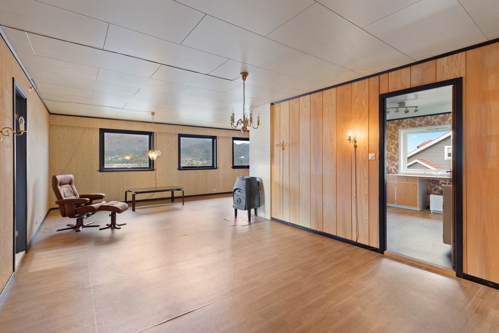 Romslig stue med belegg på gulv og plater/tapet på vegger. Galleribilde