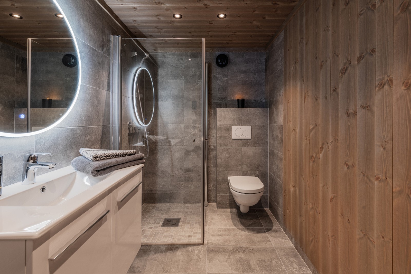 Lekkert hyttebad med eksklusive fliser kombinert med beiset veggpanel Galleribilde