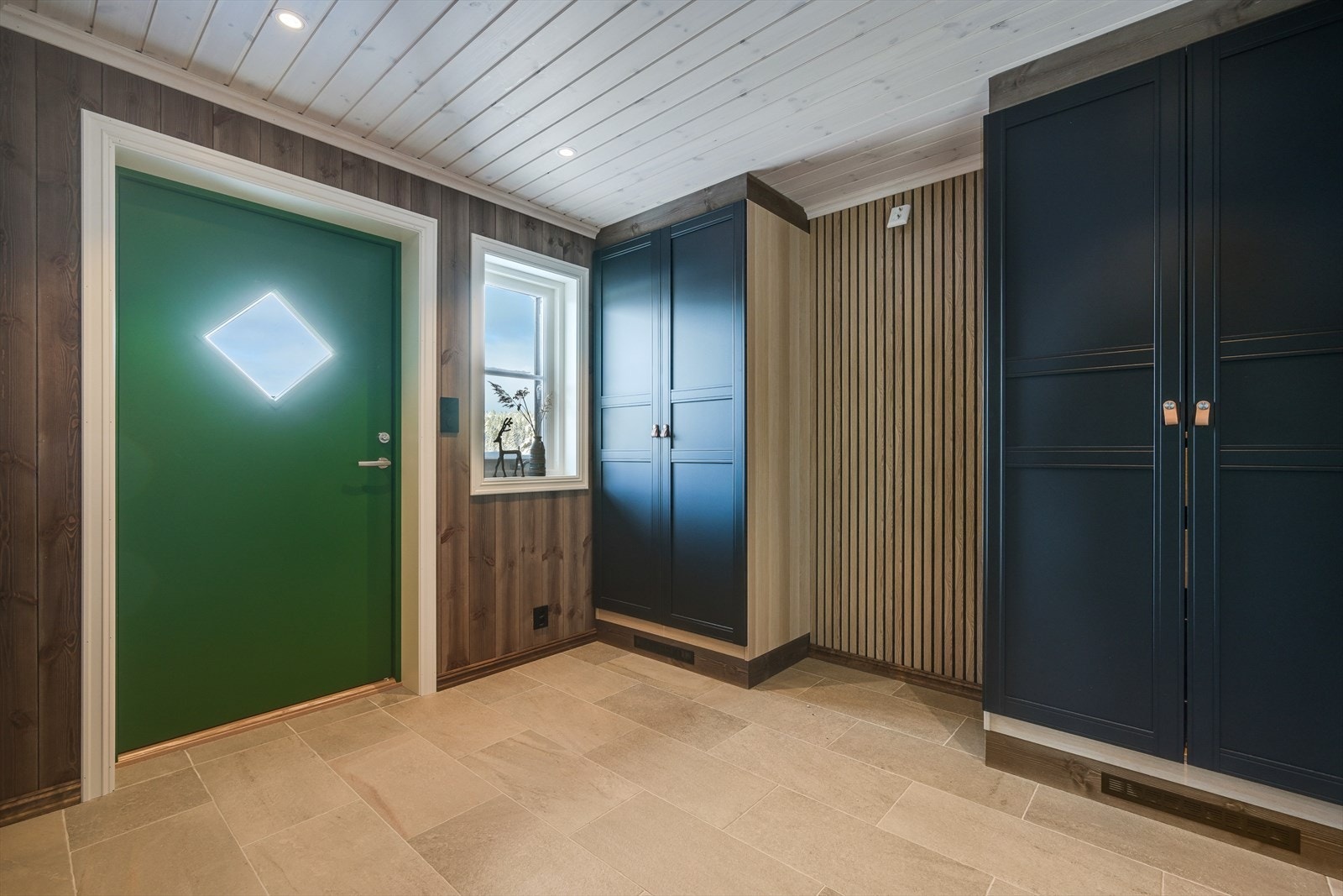 En romslig entrè med flislagt gulv og varmekabler. Godt utstyrt med skaper Galleribilde