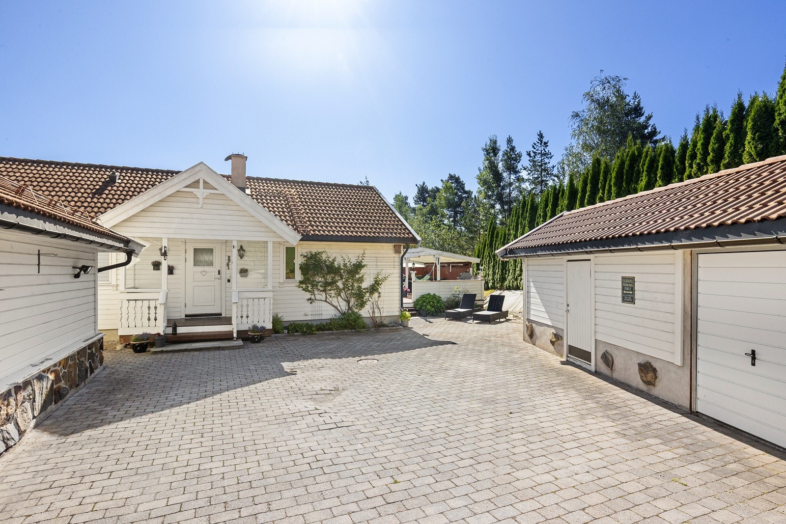 Stor gårdsplass med belegningsstein og plass til flere biler. Romslig garasje, utebod og liten garasje for sykkel-/motorsykkelparkering Galleribilde