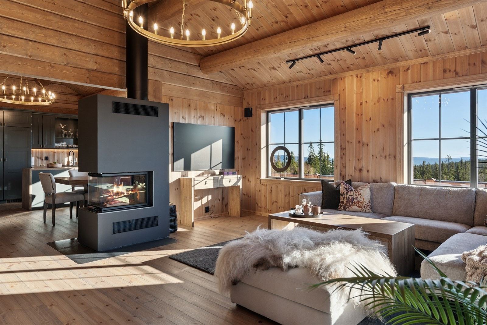 Den delvis åpne stue- og kjøkkenløsningen med mønet himling og kraftige tømmeråser gir et varmt og innbydende uttrykk. Galleribilde