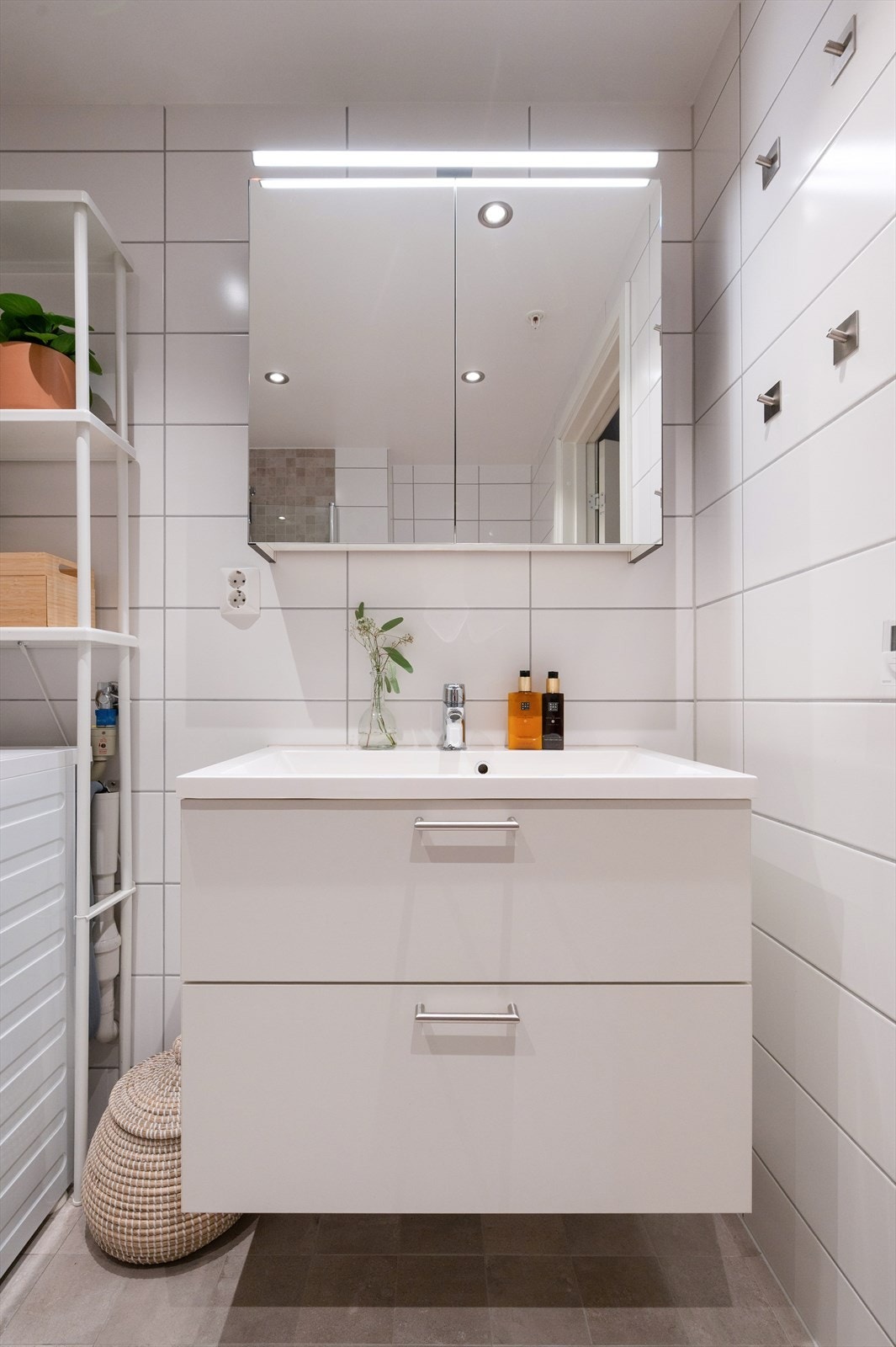 Videre er badet utstyrt med heldekkende servant med skuffeinnredning og speilskap med belysning over Galleribilde