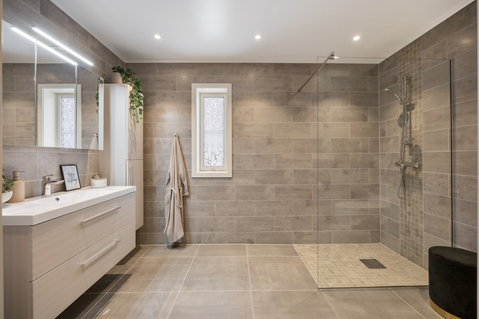 Baderomsinnredningen har lyse, finerte fronter og består av en heldekkende servant på en skuffeseksjon, et høyskap og et bredt speilskap med belysning. Galleribilde