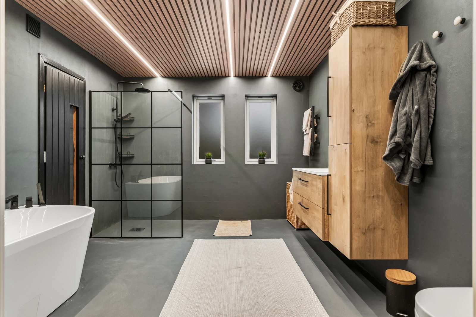 Elegant bad, med mikrosement gulv med varme. Videre inneholder badet vegghengt toalett, dusjhjørne med glassvegg, badekar, høyskap og innredning med servant. Galleribilde