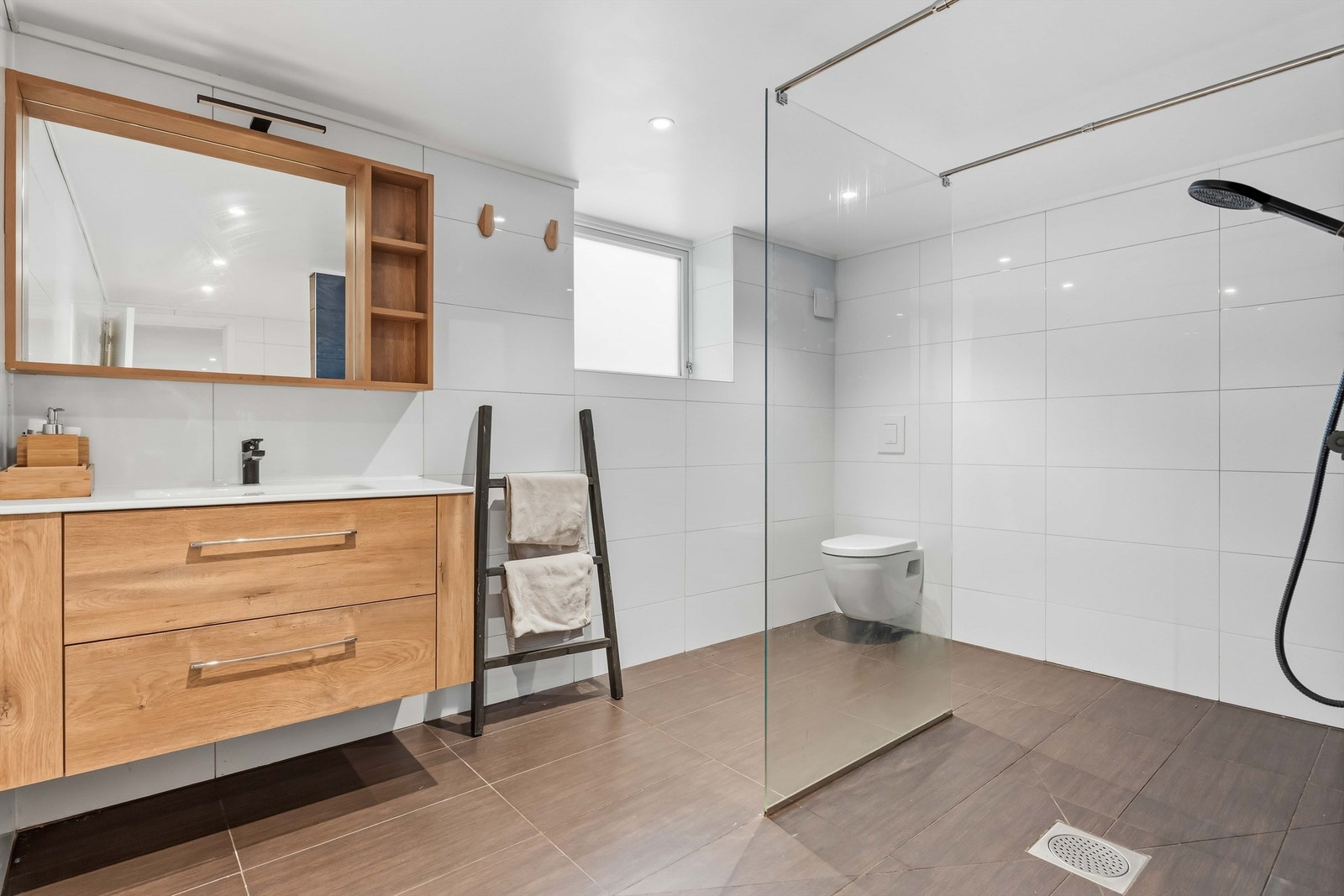 Videre er badet bestående av dusj med glassvegg, innredning med servant og vegghengt toalett. Galleribilde