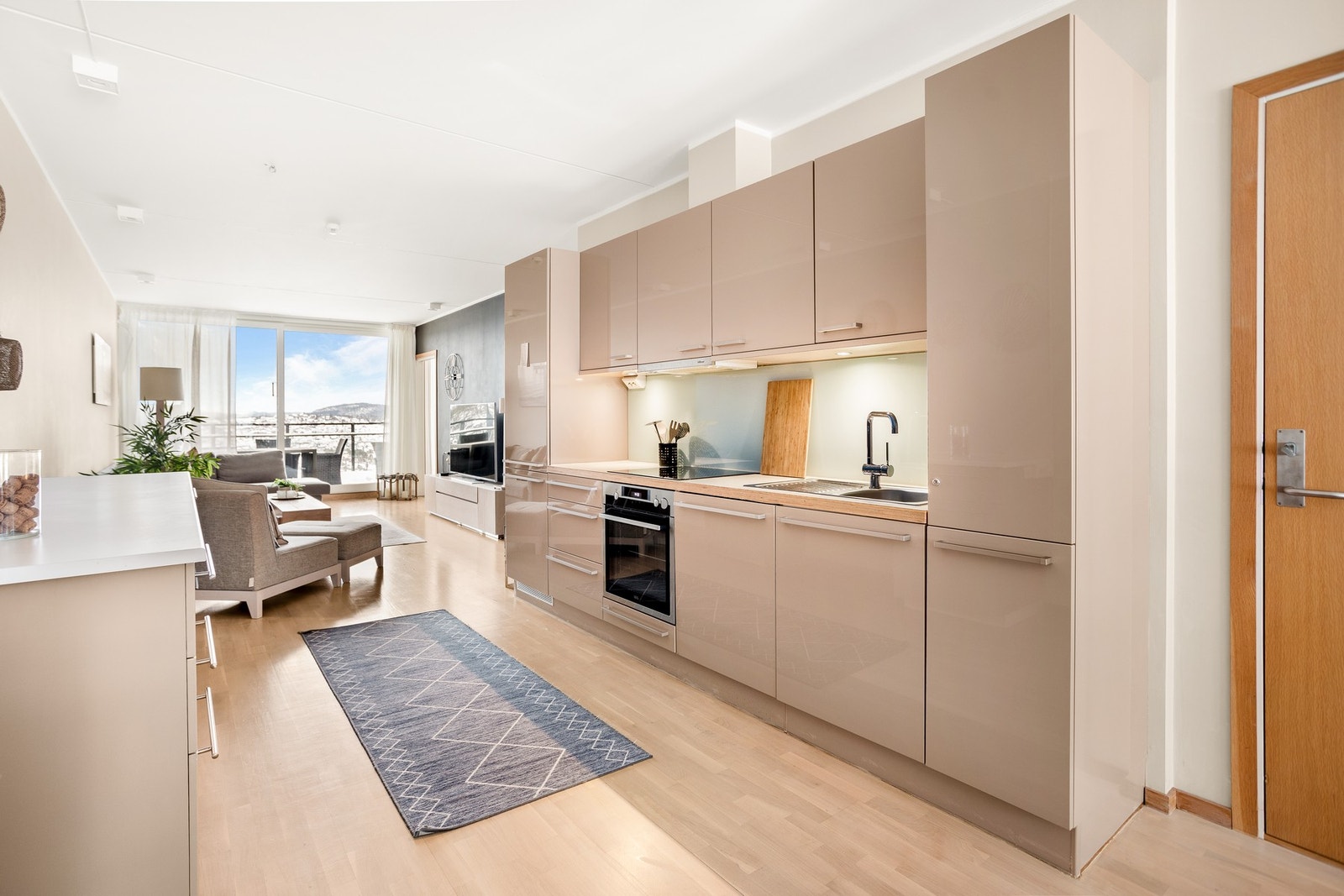 Kjøkkenet fremstår som funksjonelt og stilrent, innredet med hvite, folierte skrog og høyglans MDF-fronter. Galleribilde