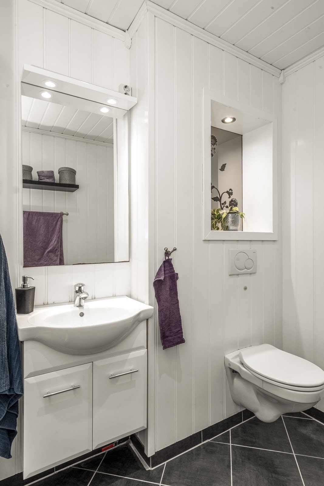 Servantinnredning med slette fronter og overliggende speil gir praktisk oppbevaringsplass. Galleribilde