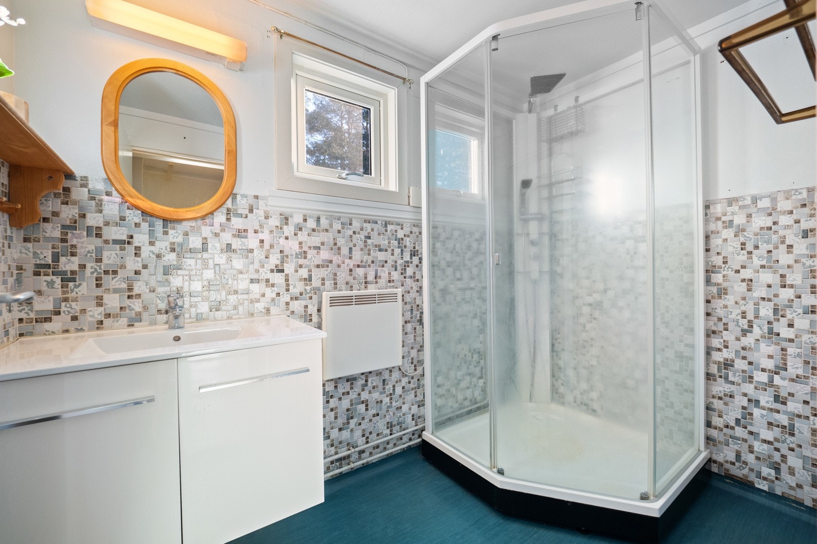 Enkelt bad med dusjkabinett og vegghengt servantinnredning. Galleribilde