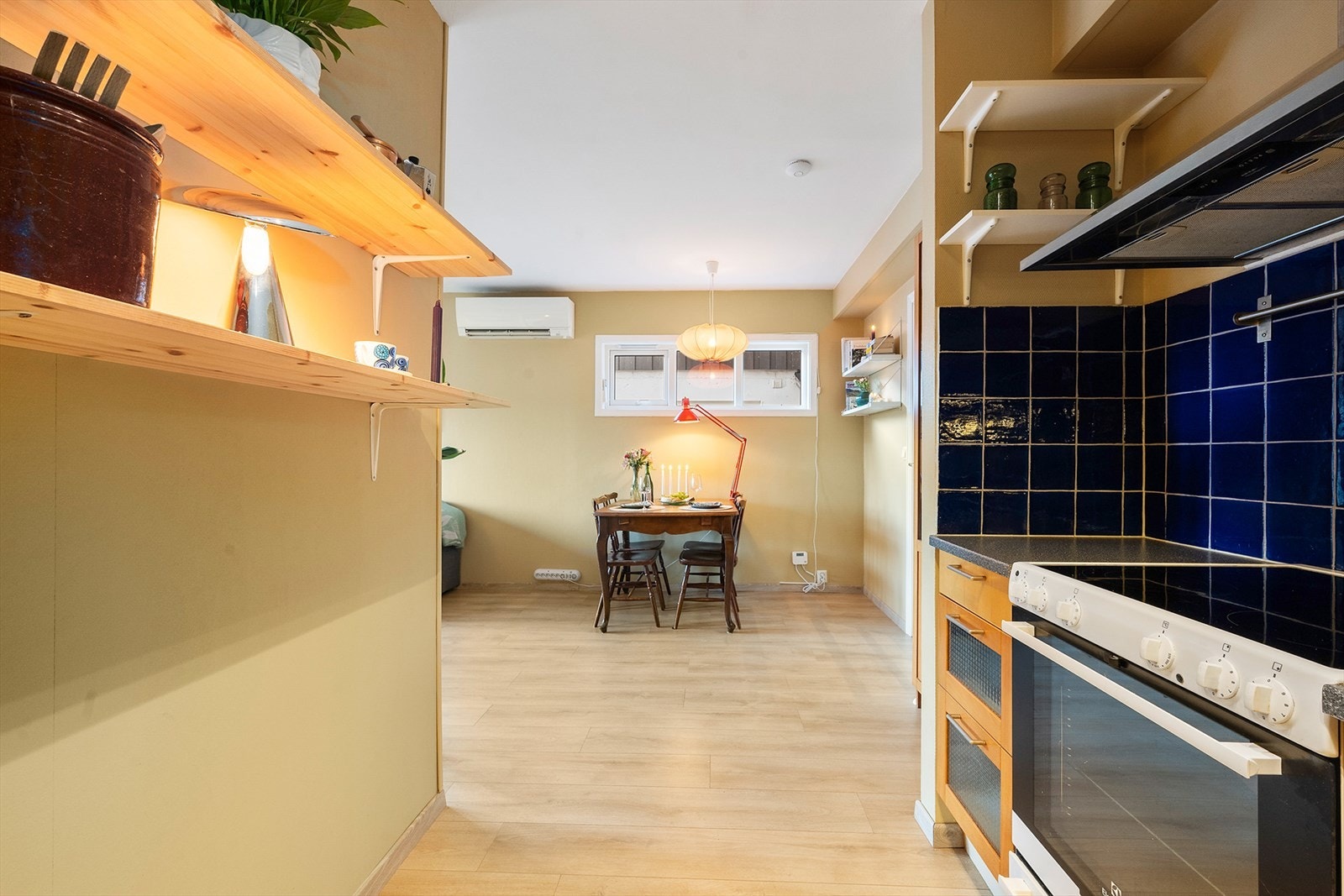 Den ene veggen på kjøkkenet har hylleinnredning med ekstra plass for oppbevaring. Galleribilde