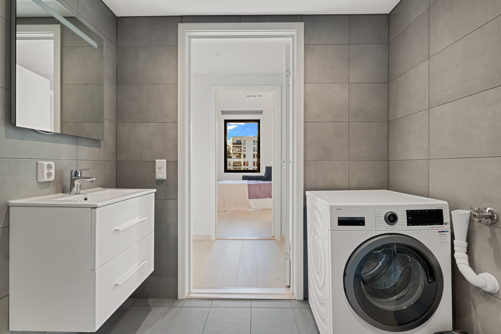 Videre har badet gulvfliser med vannbåren gulvvarme, matchende veggfliser og downlights i take. Galleribilde