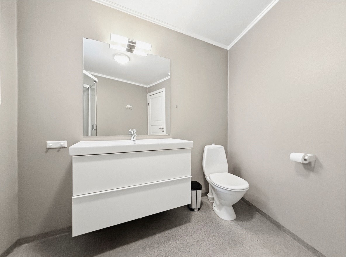 Bad med servant, speil og toalett i moderne, lyse farger Galleribilde