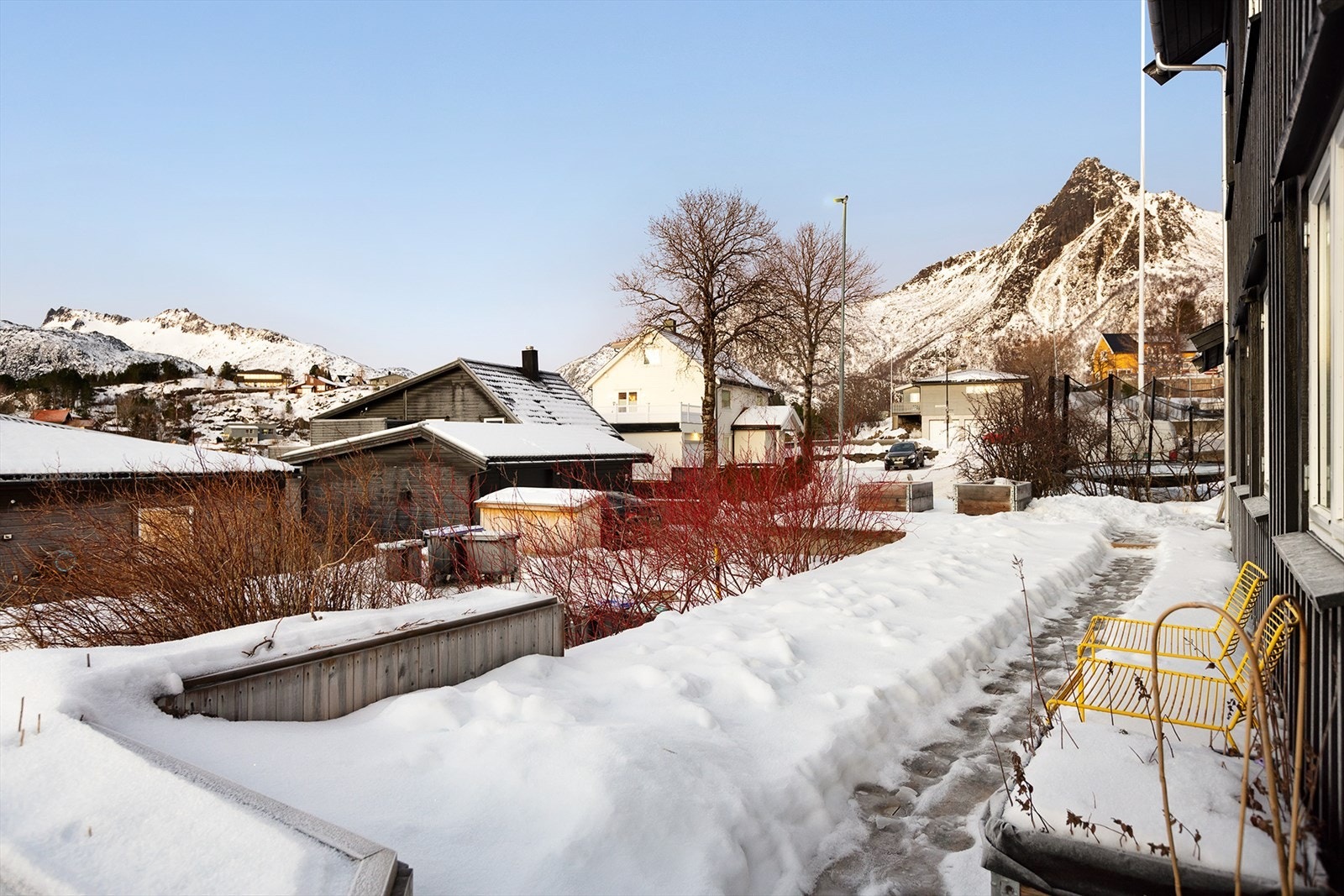 Flott uteområde som er opparbeidet med terrasse og plassbygde blomsterkasser omkranset av prydbusker Galleribilde