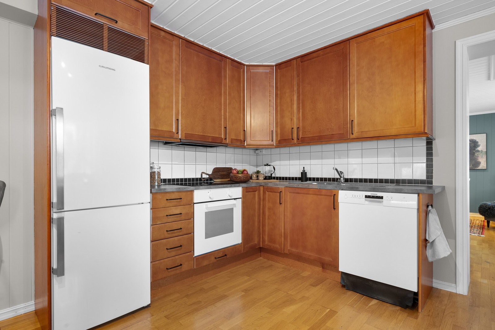 Innredningen har profilerte fronter, laminert benkeplate med nedfelt oppvaskkum og fliser i benkeryggen. Galleribilde