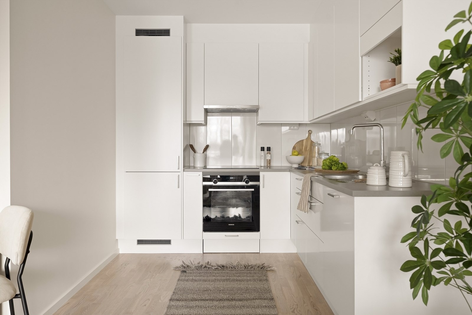 Kjøkkeninnredningen har hvite, glatte fronter og integrerte hvitevarer. Galleribilde