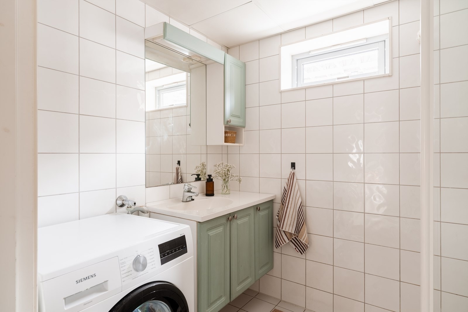 Badet er innredet med servantskap med nedfelt servant, veggskap med speil og belysning over. Galleribilde