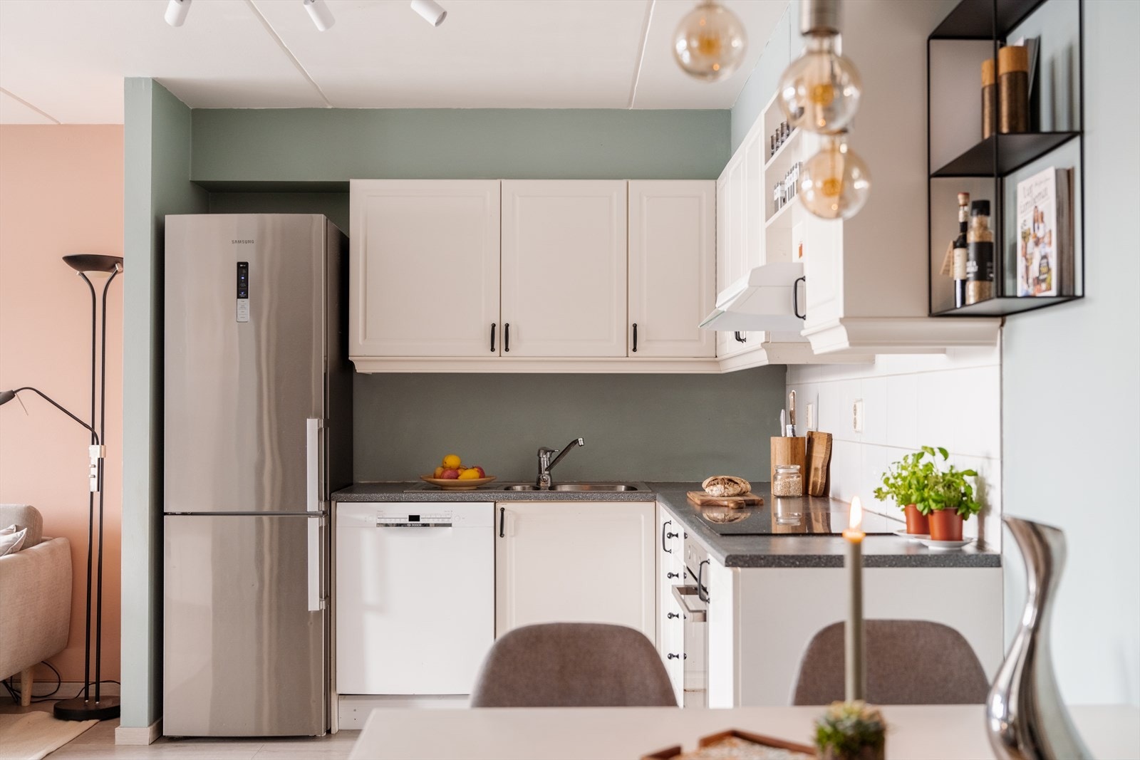 Det er montert belysning under overskap over vask, og fliser mellom benkeplate og overskap. Galleribilde