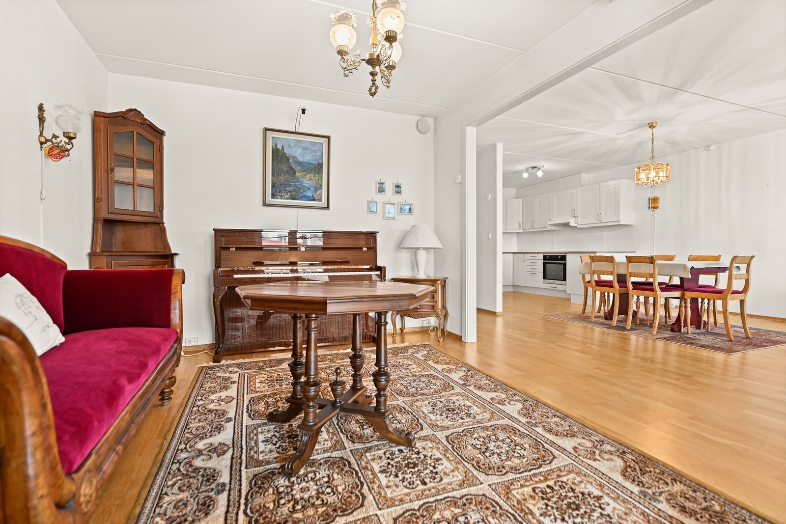 Stue med lys innredning, åpen kjøkkenløsning og spiseplass. Teppe på gulvet og lyse vegger. Galleribilde