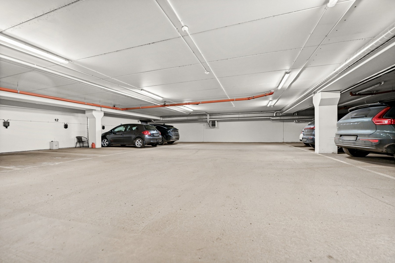 Bilde viser en innendørs parkeringsplass med flere parkeringsplasser og god belysning. Galleribilde