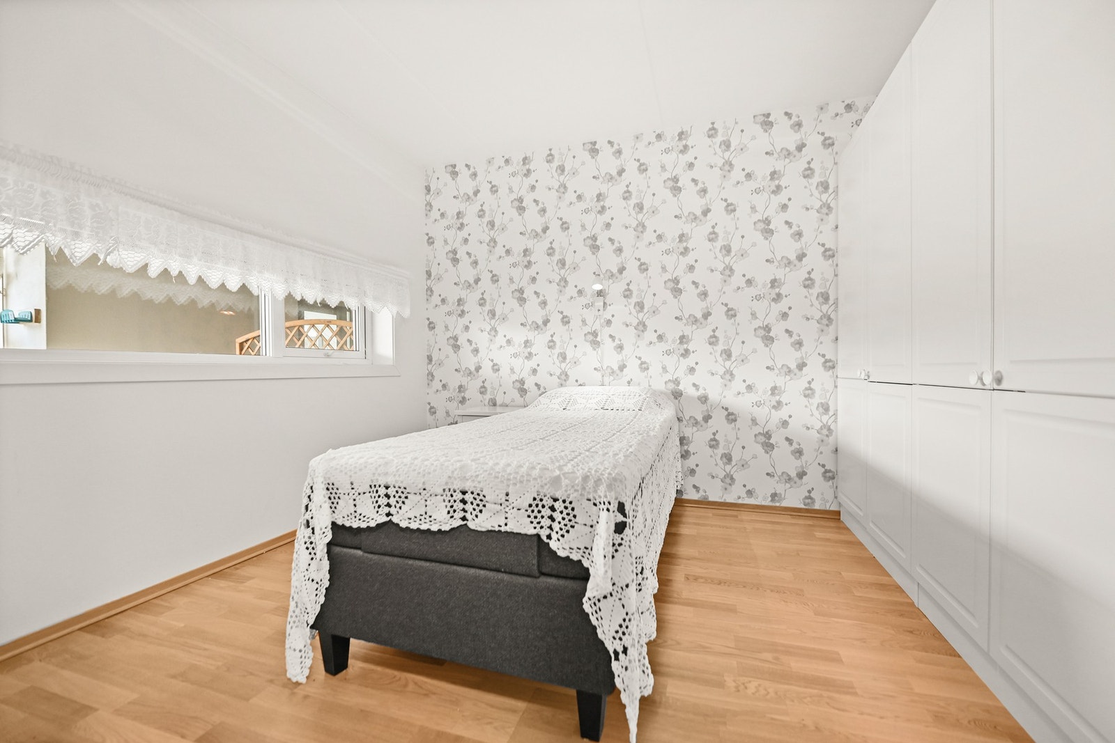 Lyst soverom med tapet på én vegg og innebygde garderobeskap. Galleribilde