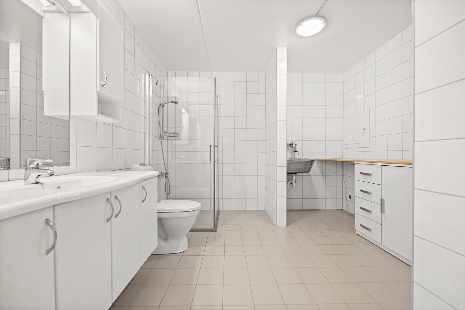 Bad med dusjhjørne, servant, toalett og vaskekrok. Flislagte vegger og gulv. God belysning. Galleribilde